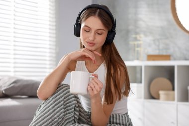 Kahveli güzel bir kadın evde müzik dinliyor.