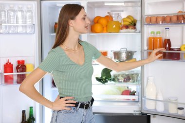 Genç kadının yanına açık buzdolabı mutfak