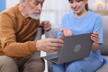 Bakım işçisi, huzurevinde dizüstü bilgisayar kullanmayı öğretiyor.