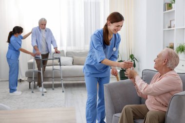 Bakım işçisi huzurevindeki yaşlı adama bir bardak su veriyor.