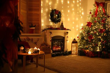 Güzel bir şömine, Noel ağacı ve karanlık odada şenlikli bir dekor. İç tasarım