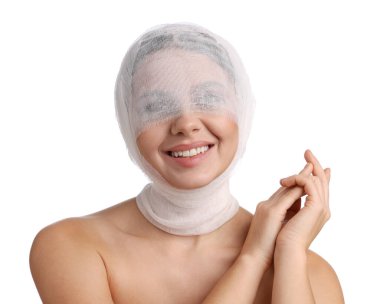 Beyaz arka plandaki estetik ameliyattan sonra yüzü tıbbi bandaja sarılı bir kadın.