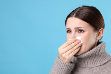 Açık mavi arka planda burnu akan bir kadın, yakın plan ve mesaj için yeri var. Soğuk Semptom