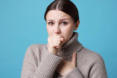 Açık mavi arka planda öksüren bir kadın. Soğuk Semptom