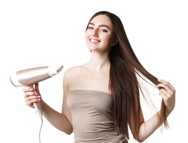 Gülümseyen kadın saçını kurutma makinesiyle beyaz arka planda kurutuyor.