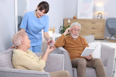 Huzurevindeki yaşlı kadına bir bardak su veren bakıcı.