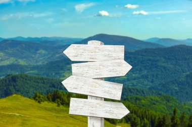 Dağların farklı yönlerini gösteren okları olan tahta tabela direği.