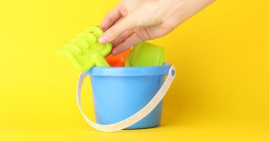 Sarı arka plana çocuklar için plaj oyuncakları koyan kadın, yakın plan.