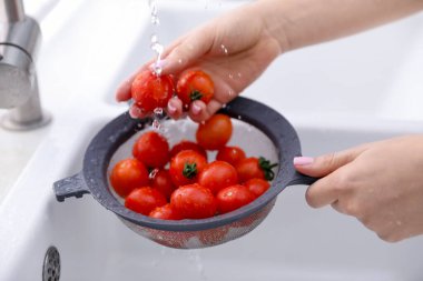 Lavaboda vişneli domatesleri elek ile yıkayan kadın, yakın plan.