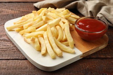 Tahta masada ketçapla servis edilen patates kızartması, yakın plan.