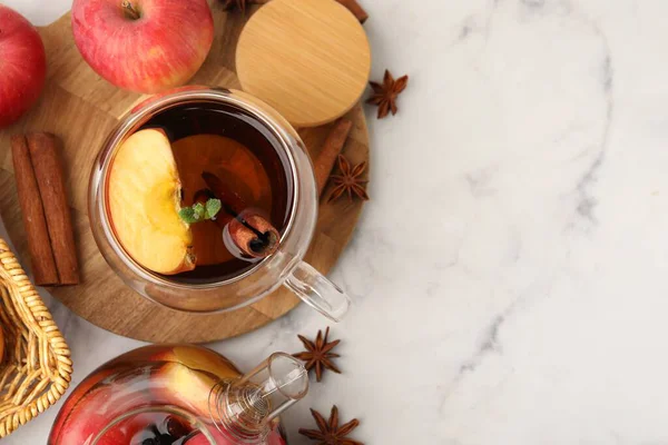 Cam fincanda Aromatik meyve çayı, çaydanlık, beyaz mermer masada elmalar ve baharatlar, düz yatak. Metin için boşluk