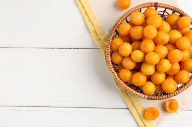 Beyaz ahşap masada, düz bir şekilde duran olgun sarı kiraz erikleri. Metin için boşluk