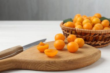 Olgun sarı kiraz erikleri ve beyaz ahşap masada bıçak, yakın plan. Metin için boşluk