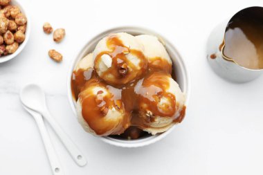 Karamel soslu lezzetli dondurma, badem ve beyaz masada patlamış mısır.