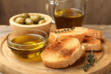 Tahtaya ekmek dilimleri, yağ, zeytin ve kekik, yakın plan.