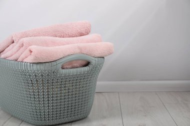 Çamaşır sepetinde yerde havlular var. Kapalı yerde, ışık duvarının yanında. Kapalı. Metin için boşluk