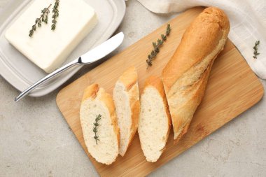 Gri desenli masada tereyağlı baget, kekik ve bıçakla kes, düz uzan.