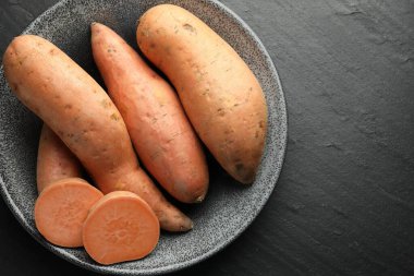 Tam ve tatlı patatesleri kasede koyu dokulu masada, üst tarafta. Metin için boşluk