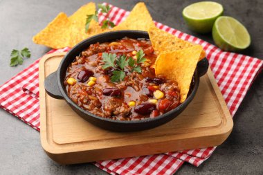 Gri masada nachos ve limonla servis edilen lezzetli biberli makarna, yakın plan.