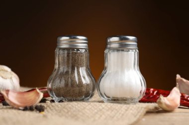 Ahşap masa üzerinde baharatlı tuzluk ve biber karıştırıcılar kahverengi eğimli arka plan, yakın çekim