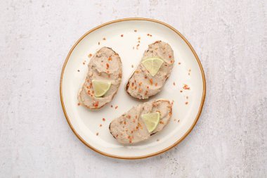 Lezzetli bruschettalar, etli börek, limon dilimleri ve ışık masasında kurutulmuş havuç taneleri.