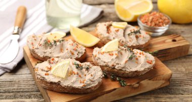 Lezzetli bruschettalar, ezme, limon dilimleri, kekik ve kurutulmuş havuç taneleri ahşap masada, yakın plan.