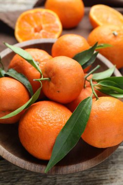 Taze mandalina ve yeşil yapraklar ahşap masada, yakın plan.