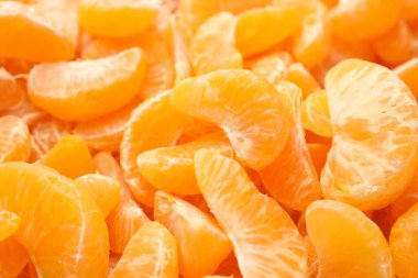 Arka plan olarak birçok olgun soyulmuş mandalina, yakın plan