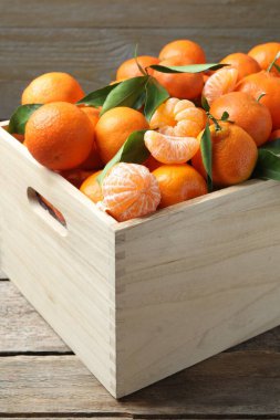 Tahta masadaki yapraklarla taze taze mandalinalar, yakın plan.