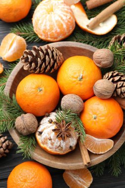 Olgun mandalinalar, baharatlar, cevizler, köknar ağacı dalları ve kozalaklar ahşap masa üzerinde, düz yatıyordu.