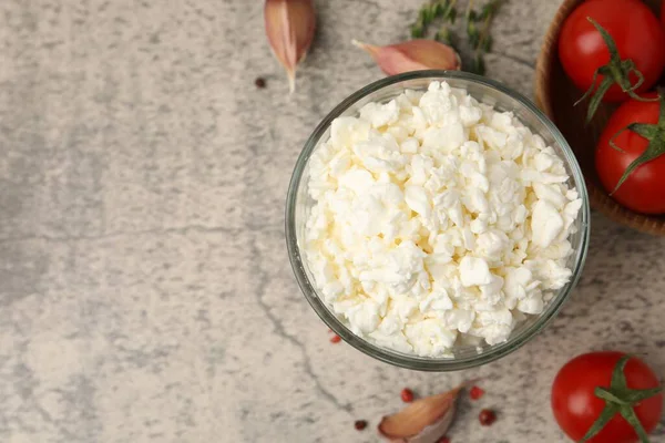 Cam kasede taze süzme peynir, gri masada domates ve baharatlar, düz yatak. Metin için boşluk