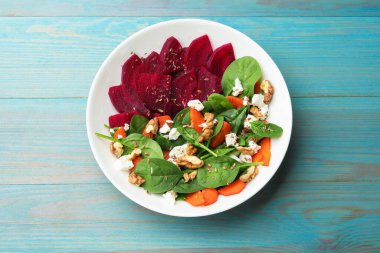 Lezzetli salata pancar, ıspanak, peynir, ceviz ve havuç ile mavi ahşap masa, üst görünüm