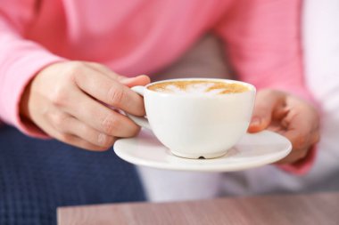 İçerideki masada bir fincan aromatik kahvesi olan kadın, yakın plan.