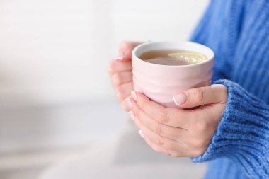 Kapalı mekanda limonlu seramik çay tutan kadın, yakın plan. Metin için boşluk