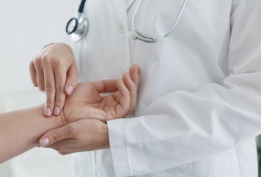 Doktor klinikte adamın nabzını kontrol ediyor.