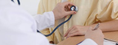 Doktor hastanede steteskopla kadının kalp atışlarını kontrol ediyor.