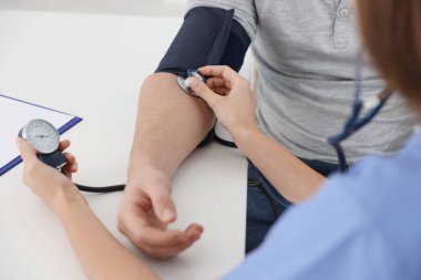 Hemşire hastahanedeki masada kan basıncını sphygmomanometre ile ölçüyor.