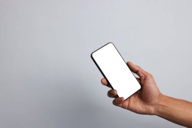 Açık gri arka planda boş ekranlı akıllı telefon tutan adam, yakın plan. Tasarım için model