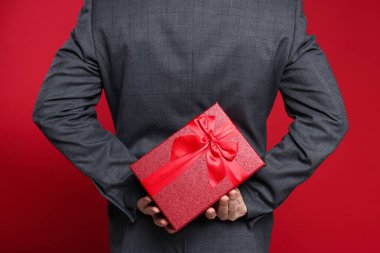 Sevgililer Günü. Kırmızı arka planda hediyeli adam, arka planda