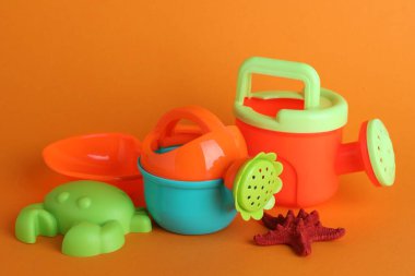 Parlak çocuk plaj oyuncakları ve turuncu arka planda denizyıldızı