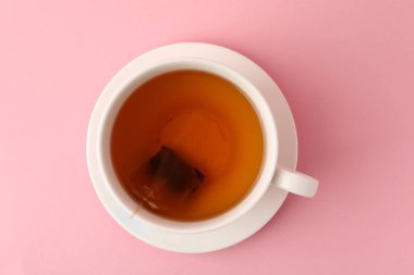 Çay demleniyor. Pembe arka planda çay poşeti, üst manzara.