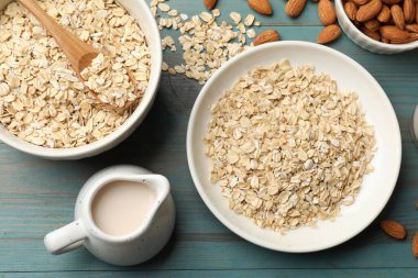 Yulaf gevreği, badem sütü ve fındık açık mavi ahşap masa, düz uzanmış