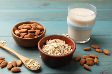 Yulaf gevreği, badem sütü ve açık mavi ahşap masada fındık, yakın plan.