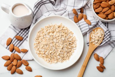 Yulaf gevreği, badem sütü ve fındıklar beyaz mermer masada, düz yatıyordu.