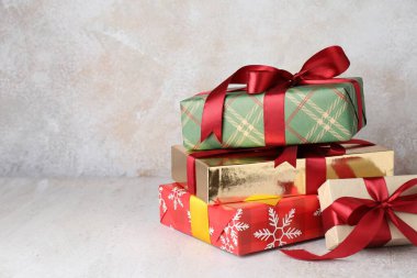 Many decorated Christmas gifts on light background, closeup. Space for text
