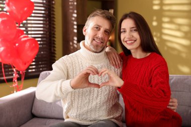 Mutlu çift içeride elleri ile kalp yapıyor. Sevgililer Günü kutlaması