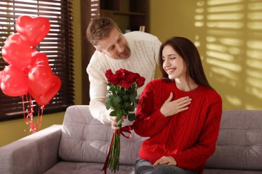 Mutlu adam içeride gül buketiyle kız arkadaşına sürpriz yapıyor. Sevgililer Günü kutlaması