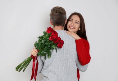 Bir buket gülle erkek arkadaşına sarılan mutlu bir kadın. Sevgililer Günü kutlaması