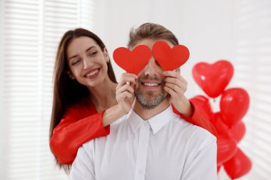 Kapalı alanda kağıt kalpli mutlu bir çift. Sevgililer Günü kutlaması