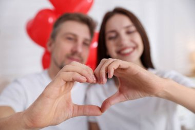 Mutlu çift, elleri kapalı, seçici bir odak ile kalp yapıyor. Sevgililer Günü kutlaması
